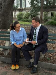 Taylor Grooms listening to a client on a bench in downtown Charleston