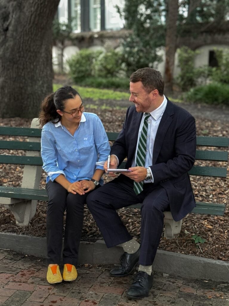 Taylor Grooms listening to a client on a bench in downtown Charleston