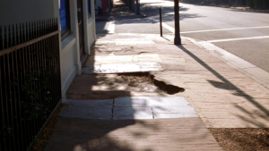 Cracked and uneven historic sidewalk pavement on a downtown Charleston street, South Carolina